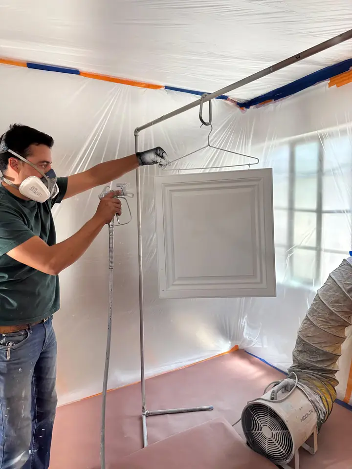 Master Painting crew member spray finishing a cabinet door