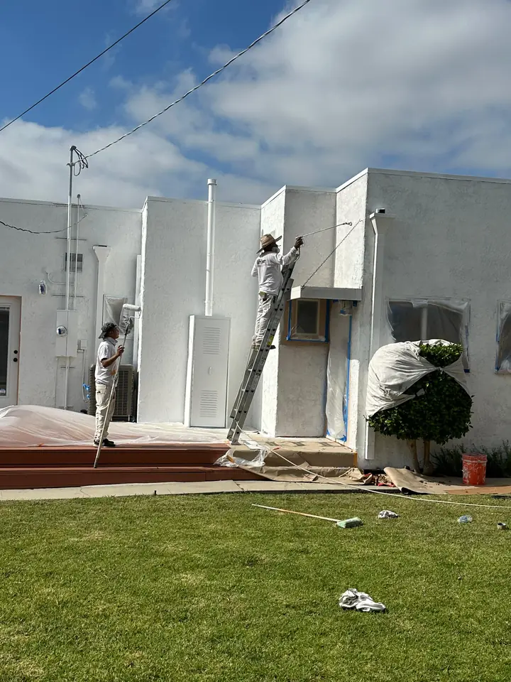 Master Painting crew member on a ladder painting a home exterior