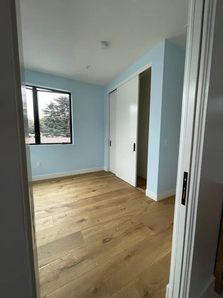 Hallway with hardwood floors and soft blue painted walls