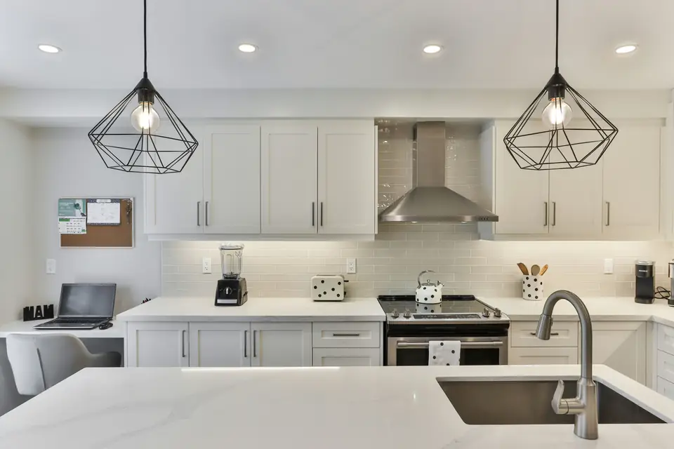 Modern white kitchen with marble island and pendant lighting after a full repaint
