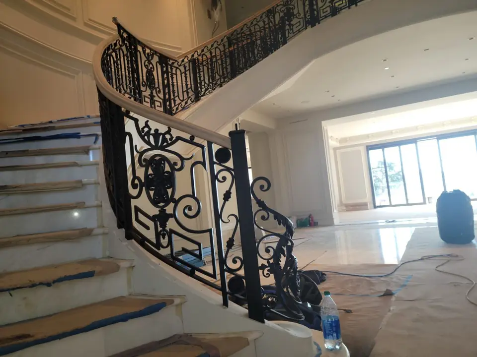 Painter working on a curved staircase railing during a residential project