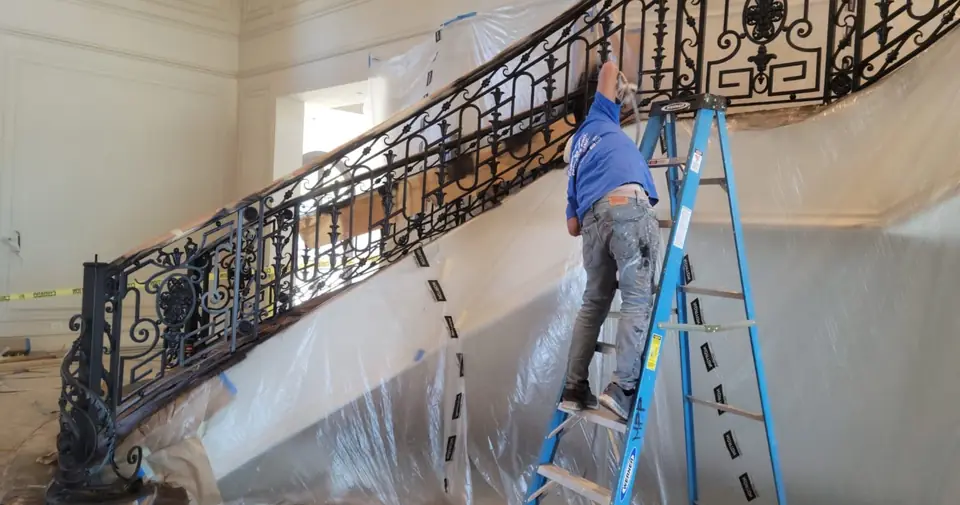 Grand curved staircase with wrought iron railing after painting